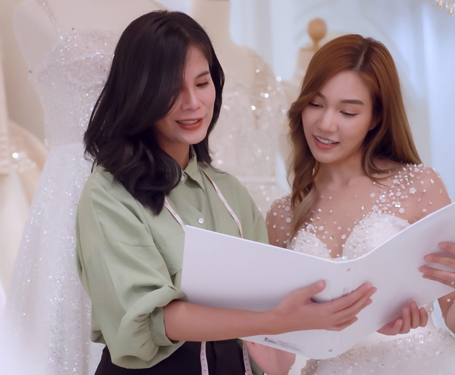 The owner of a wedding dress shop is offering a different type of bridal dress to the bride.